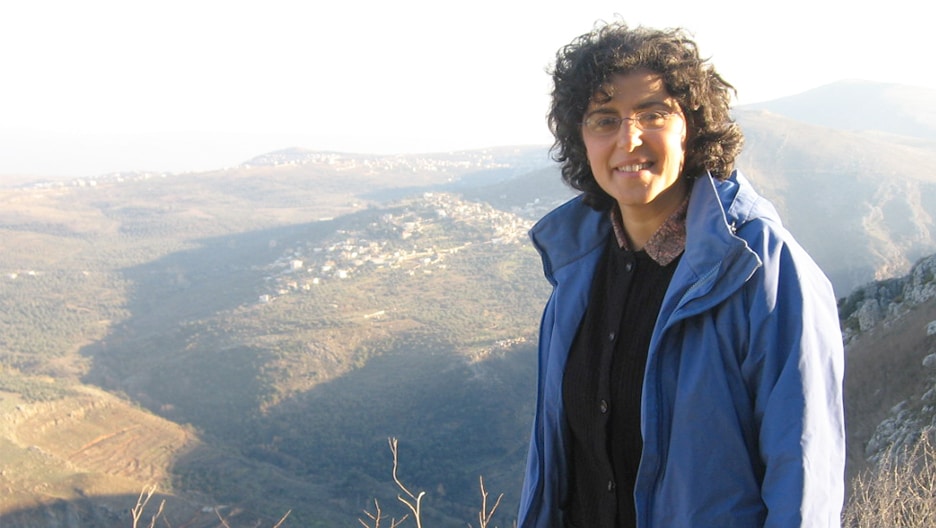Amal Morcos looking at the camera in front of a landscape in southern Lebanon