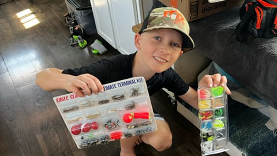 Osteosarcoma patient Toby holding up fishing supplies received through a care package (via a referral from OSI Connect)
