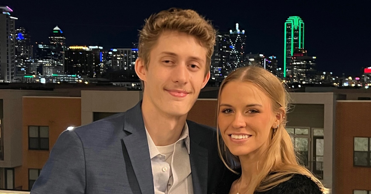 Jarred Meyer and Chloe Anderson standing together on a roof at nigh, with a city skyline behind them