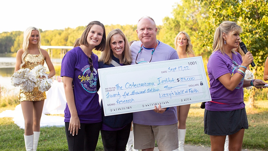 Vanessa Peterson, Amy Lobner, John Wampler, and Jennifer Wampler at Lizzy's Walk of Faith 5K, holding a check addressed to the Osteosarcoma Foundation