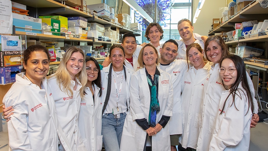 Dr. Crystal Mackall and her lab at Stanford University, smiling and looking into the camera.