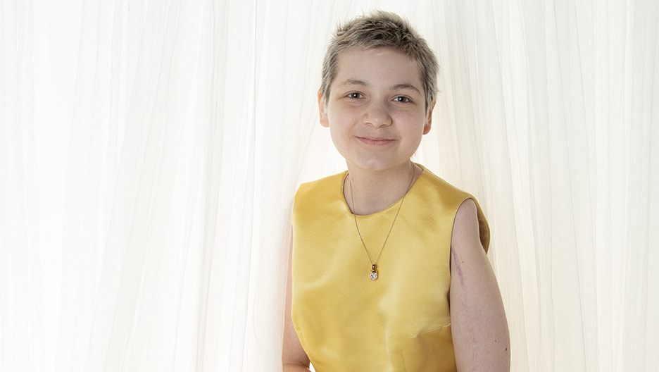 Photo of Grace smiling and wearing a yellow dress.