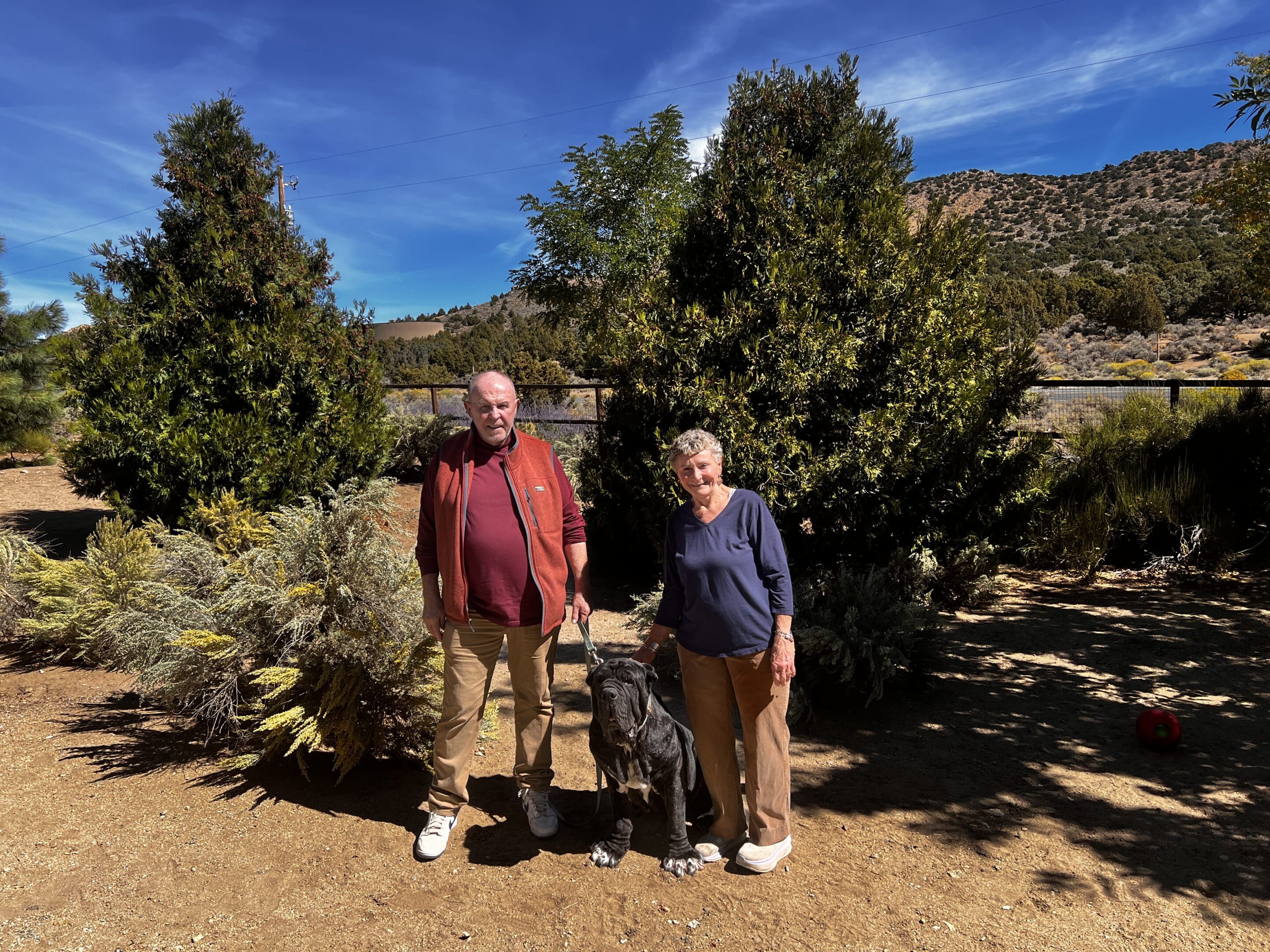 Robyn Roth and Mack McKinley standing outside in nature with their dog, Bella Bellona