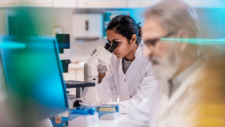 Researcher looks into microscope.