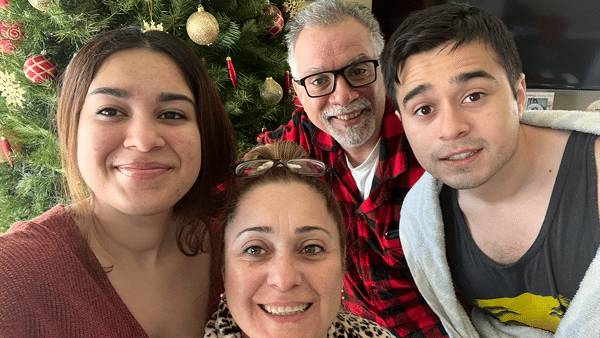 Dylan posing with his family in front of a Christmas tree