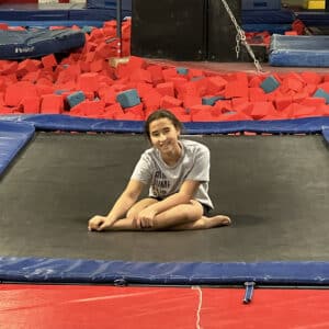 Angie sitting with legs crossed on a trampoline