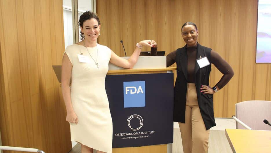 Two women pose in front of a podium with the FDA and OSI logos.